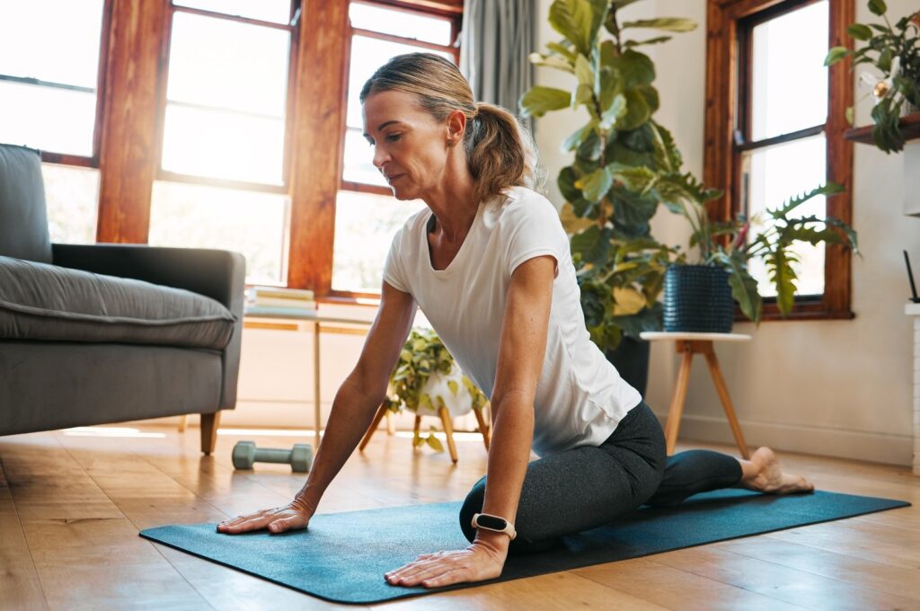 Woman, yoga and pigeon pose stretching in house or home living room for relax exercise, training an